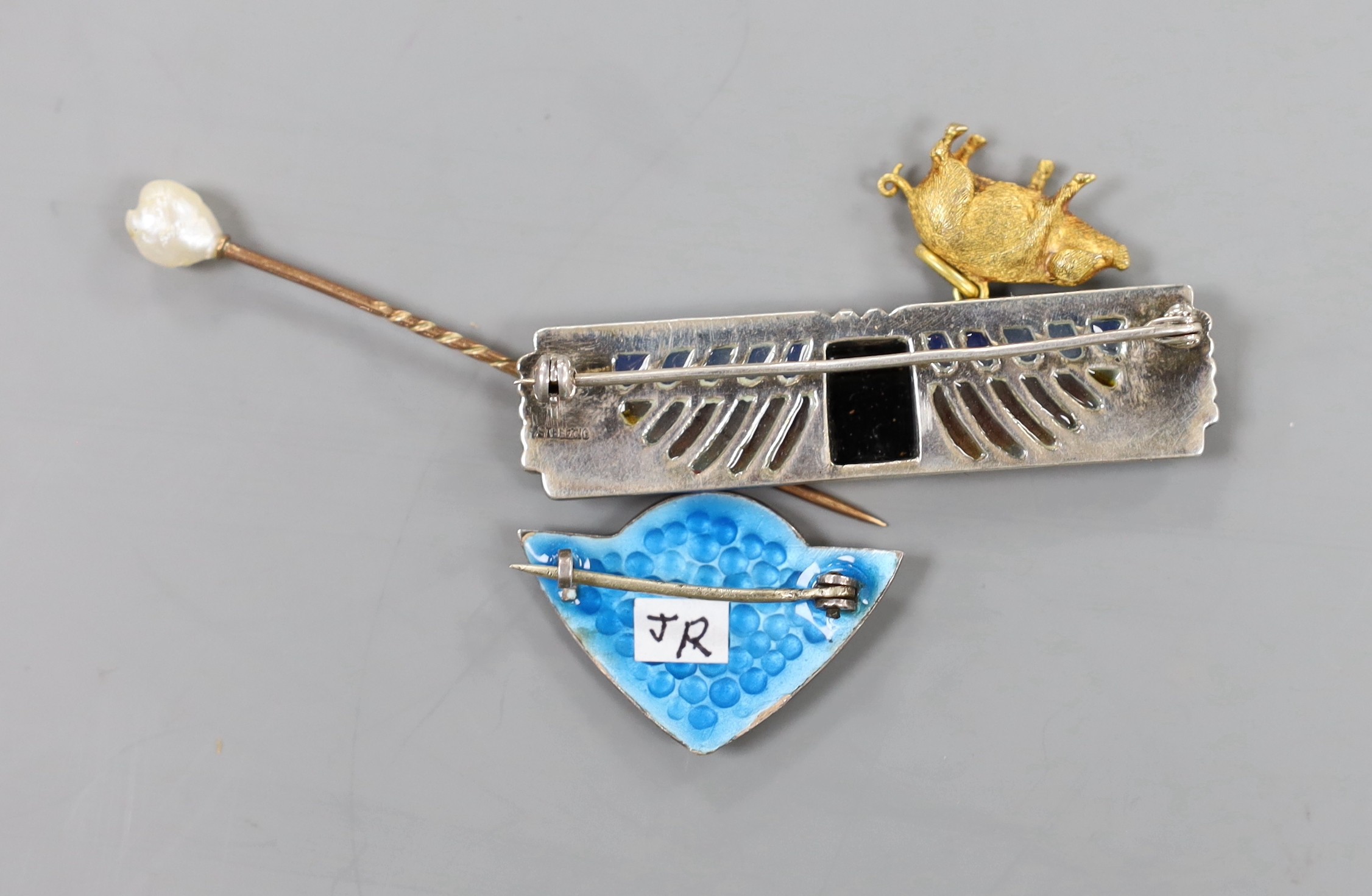 An Art Deco white metal, plique a jour, black onyx and marcasite set rectangular brooch, 54mm, a three colour enamelled brooch, a yellow metal and facetted garnet bead necklace, a 9ct pig charm and, a cloak pin? and a ba